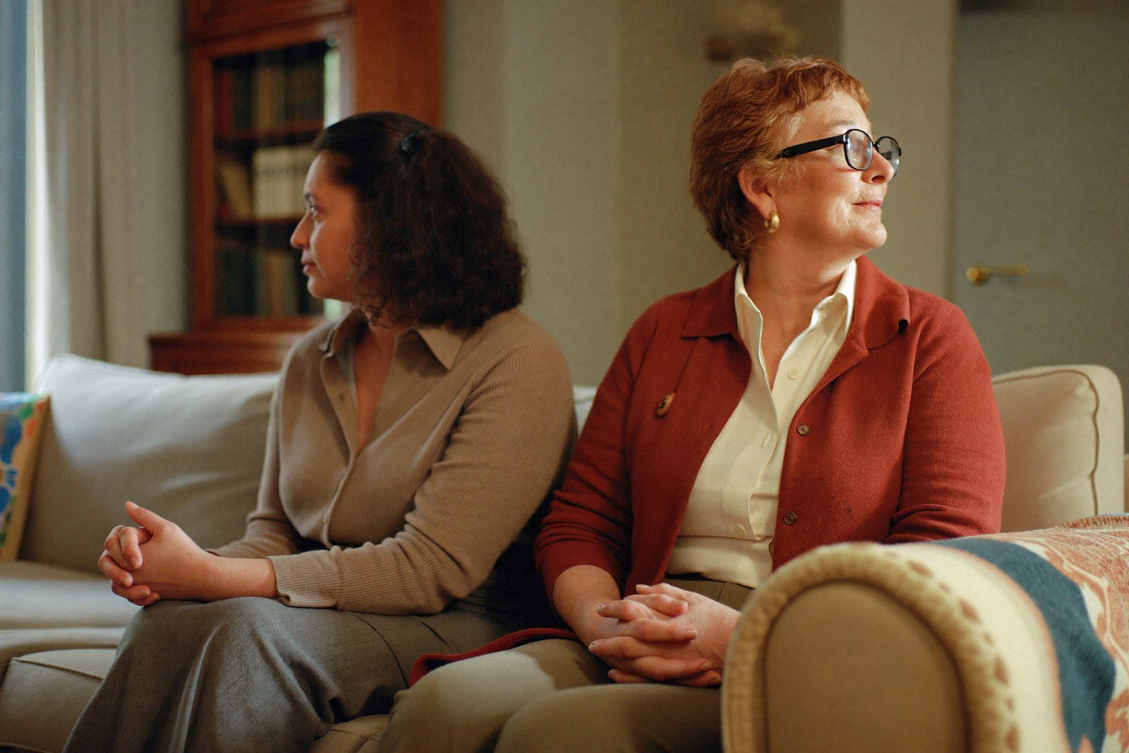 Tochter und Mutter sitzen still nebeneinander auf dem Sofa